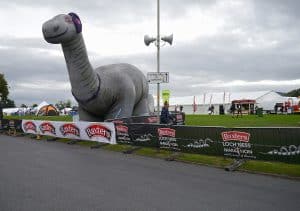 Inflatable Nessie beside Baxters Loch Ness Marathon barriers at the Bught Park Event Village in Inverness