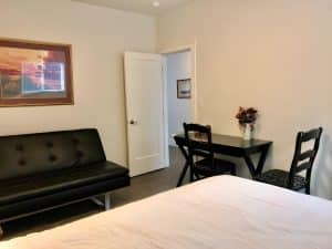 A guest room with a black leather sofa bed and a small dining table with two chairs