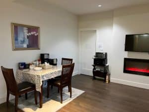 The breakfast table in the common area, set with a coffee maker and kettle beside an electric fireplace