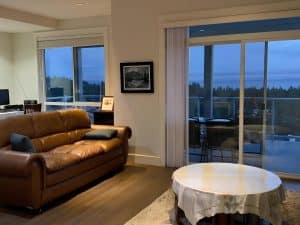 Leather sofas and sliding balcony doors in the shared lounge at Ocean Melody Vacation Rooms, with the sea visible through the glass