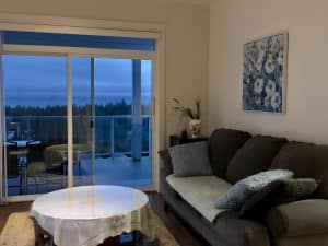 The shared lounge at dusk, with the balcony furniture visible through the sliding doors