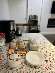 The self-serve breakfast laid out on the common-area table, with a coffee maker, jam and crockery