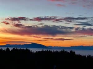 A pink and blue sunset over the sea and distant mountains from the North Nanaimo shore