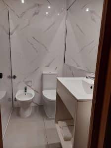 A refurbished bathroom at the Petrus Hotel, marble-effect tiling with a white vanity unit and a bidet