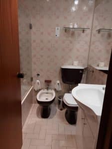 An older bathroom at the Petrus Hotel with patterned wall tiles, a toilet and a bidet