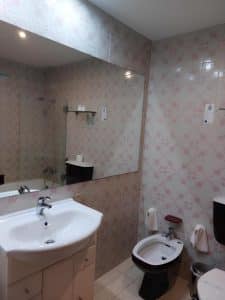 A bathroom at the Petrus Hotel with a large mirror above a washbasin and patterned tiling