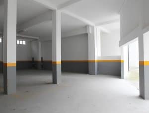 The empty underground garage at the Petrus Hotel in Chaves, painted concrete pillars with a yellow line around the walls