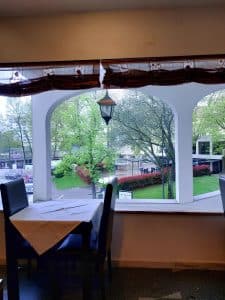 A table set beside an arched window at the Petrus Hotel, looking out onto a tree-lined square in the centre of Chaves