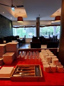The breakfast room at the Petrus Hotel set with stacked plates, glasses and cutlery