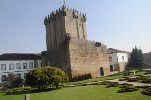 The granite keep of Chaves Castle rising above clipped formal gardens, with the town's rooftops around it
