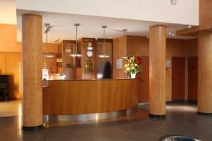 Curved wooden hotel reception desk with a service bell, where check-in registration takes place