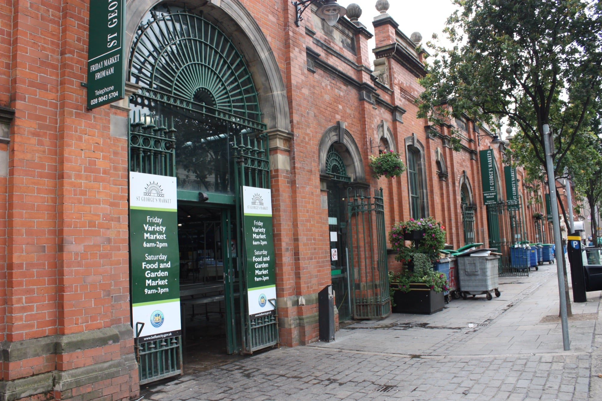 The red brick exterior and green ironwork entrance of St George&rsquo;s Market in Belfast