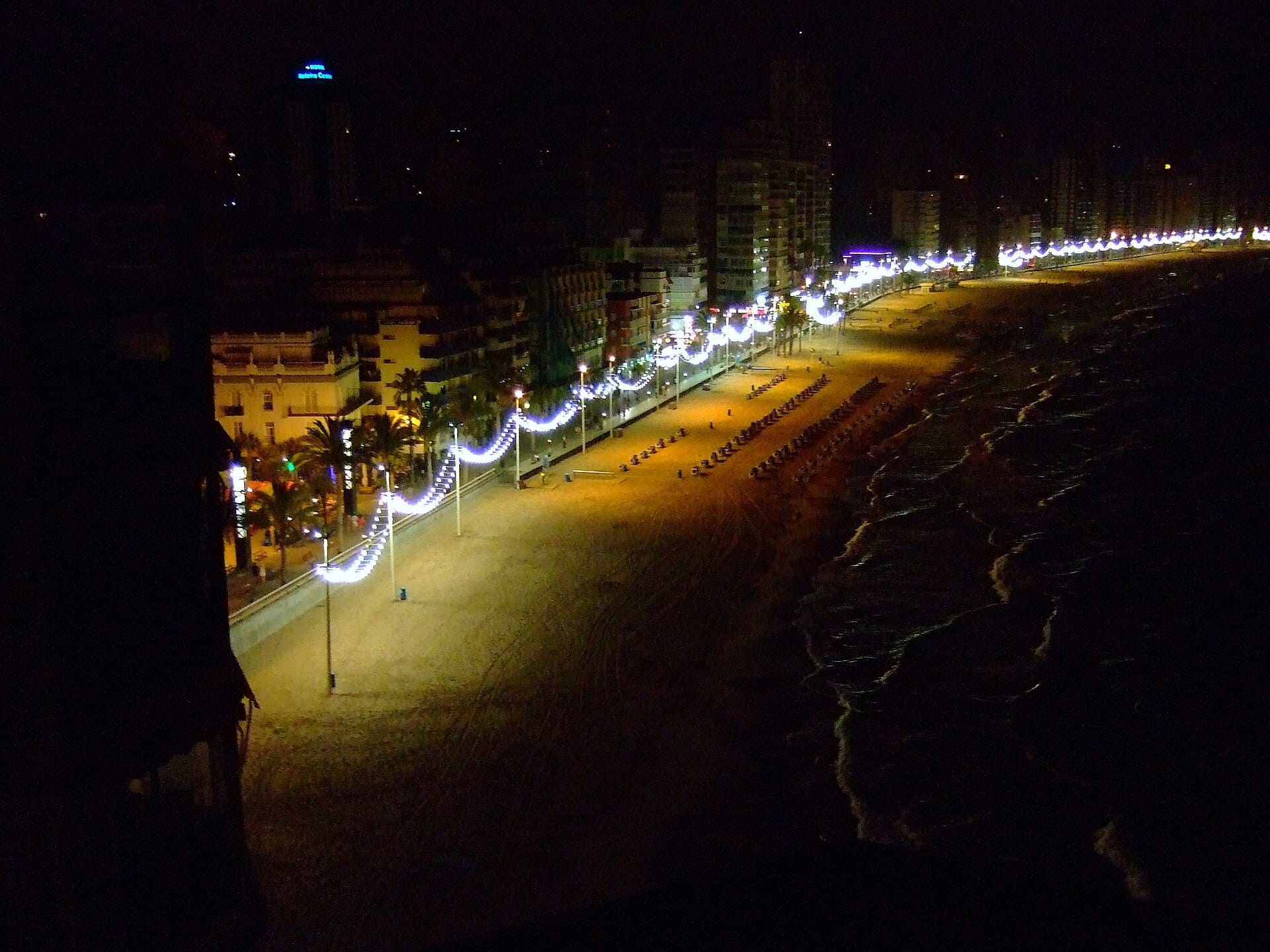 The Levante promenade in Benidorm at night, its lamp posts lit in loops along the empty beach and the sea