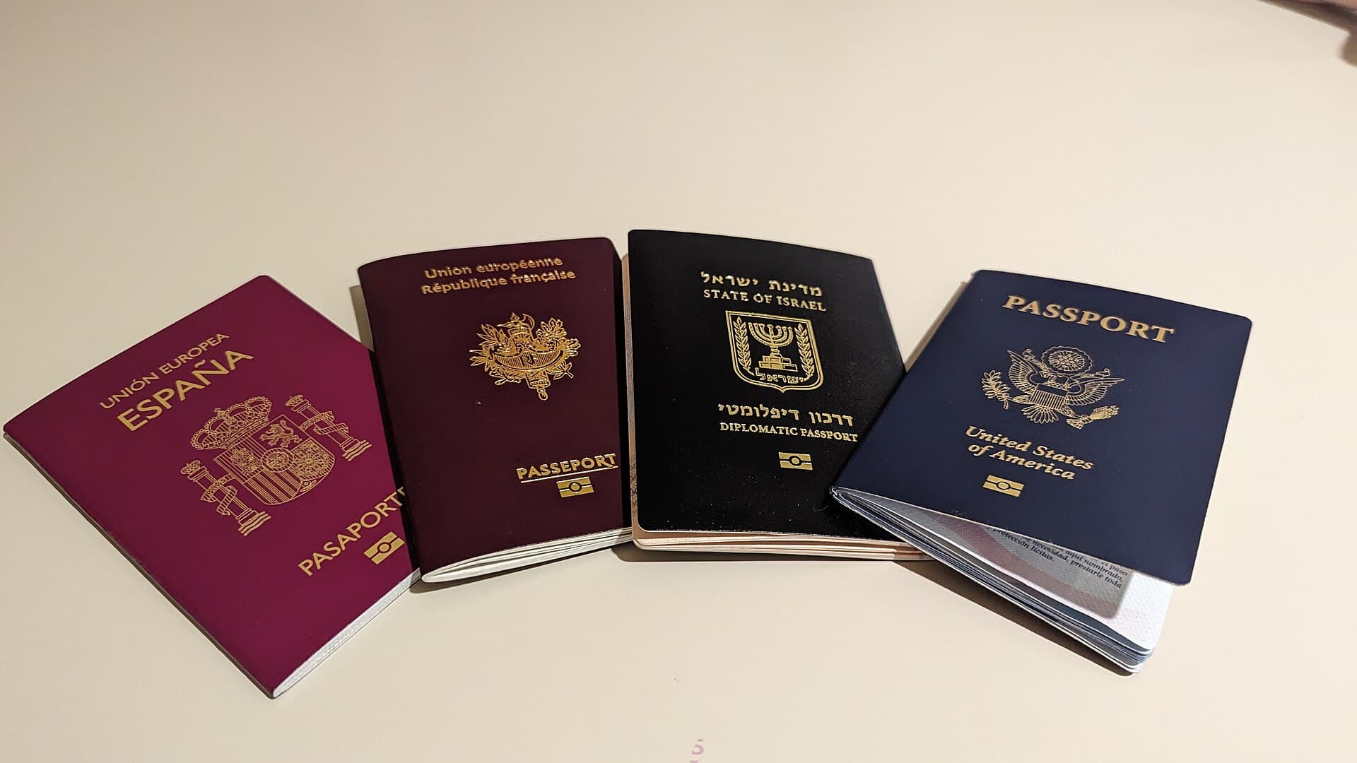 Four closed passport covers on a table, from Spain, France, Israel and the United States