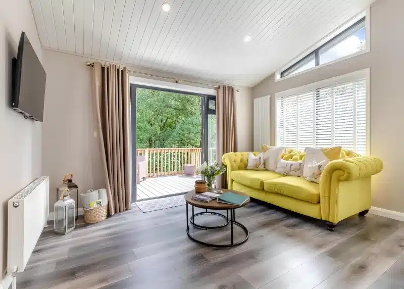 a living room with a yellow couch and a table at Charlesworth Lodges in Glossop