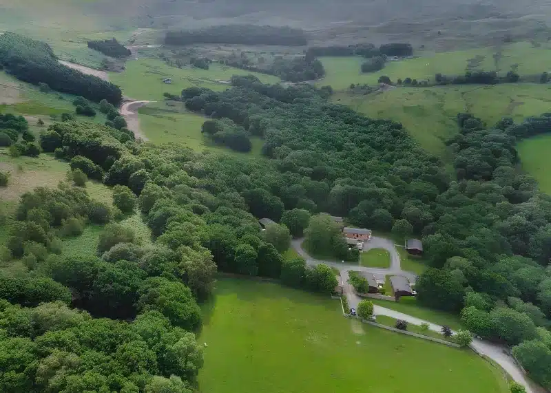 an aerial view of a road in a field with trees at Charlesworth Lodges in Glossop