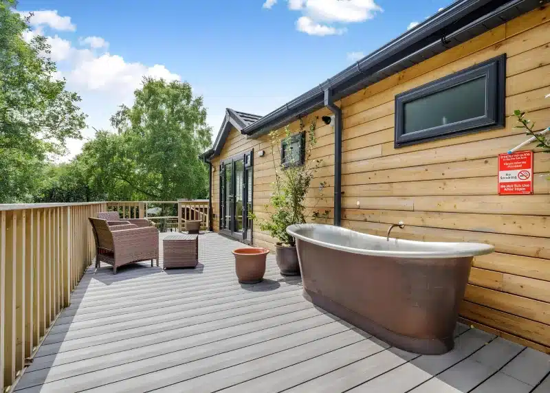 a tub sitting on a deck next to a house at Charlesworth Lodges in Glossop