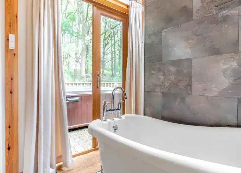 a bath tub in a bathroom with a window at Charlesworth Lodges in Glossop
