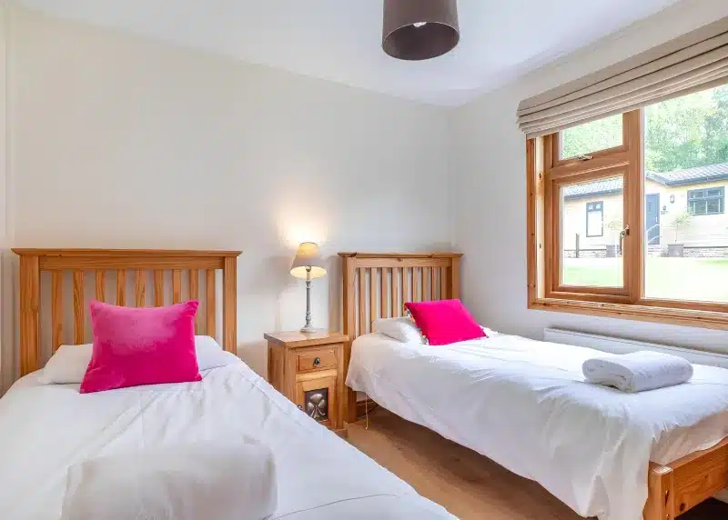two beds in a room with two pink pillows at Charlesworth Lodges in Glossop