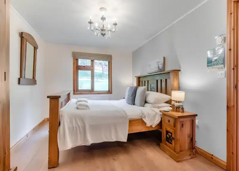 a bedroom with a large bed and a chandelier at Charlesworth Lodges in Glossop