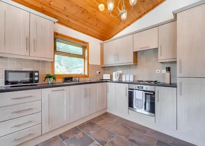 a large kitchen with wooden cabinets and a ceiling at Charlesworth Lodges in Glossop