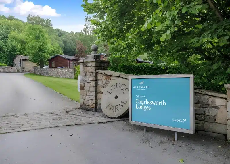 The Lodge Farm entrance, with a millstone set in a stone pier and a Charlesworth Lodges sign.