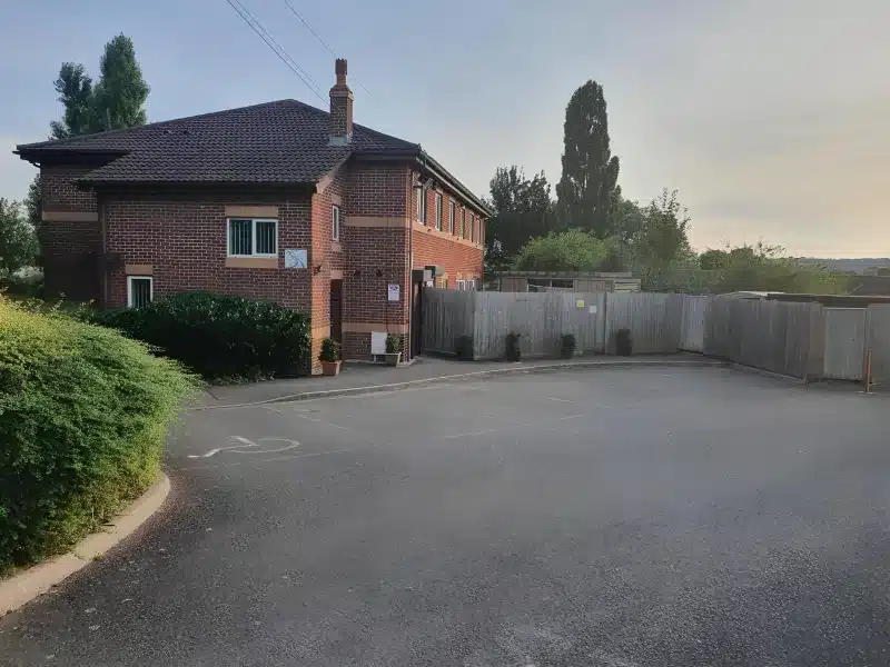 The brick building at Dan's Homestay, with a wooden gate and an asphalt forecourt.
