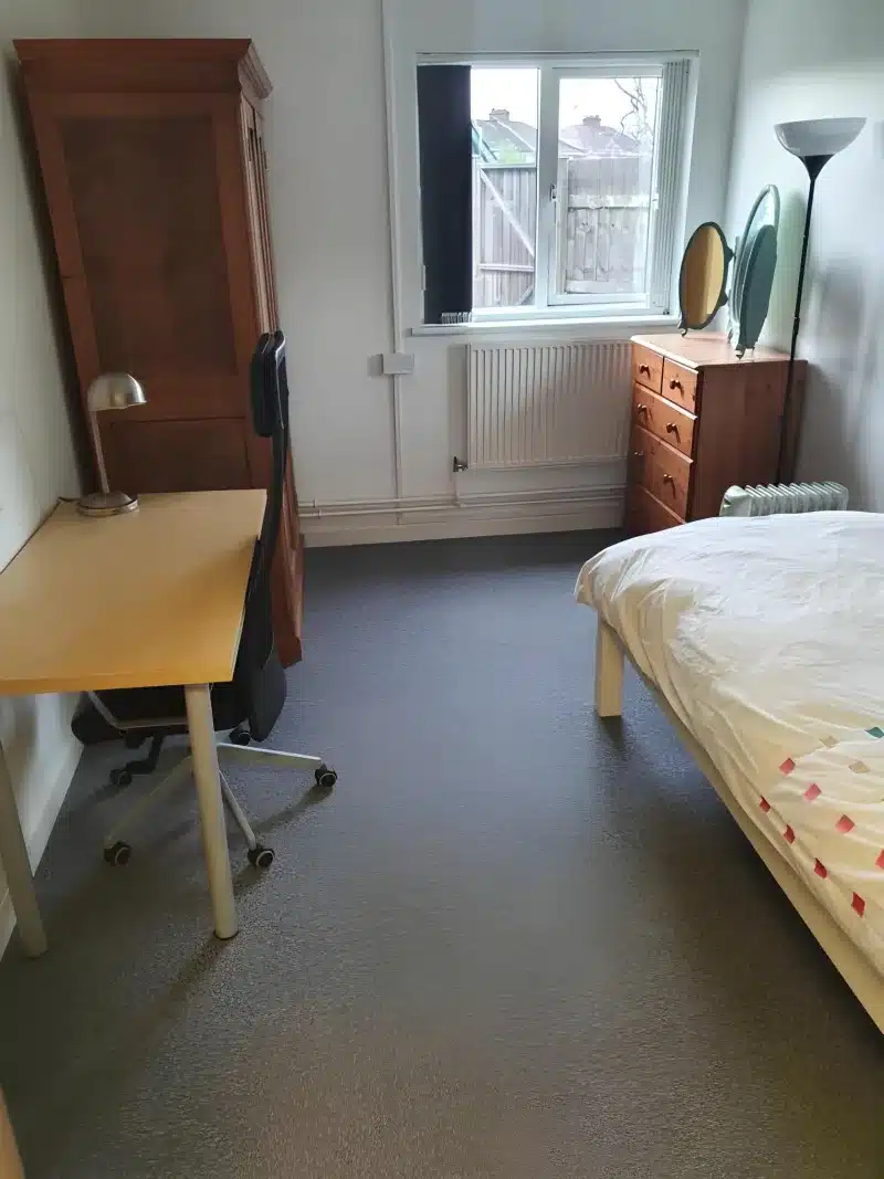 Standard single room with a desk and office chair, a pine wardrobe, a chest of drawers with two mirrors, a radiator and a single bed by the window