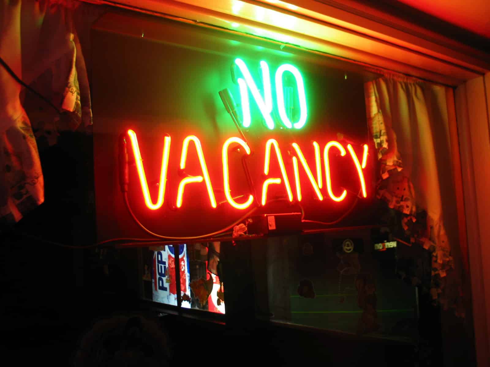 Green and red neon NO VACANCY sign lit in a window