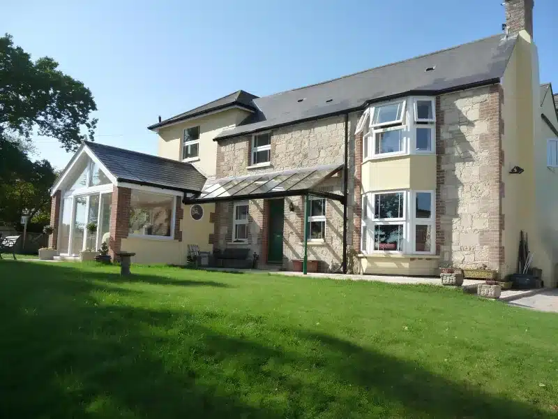 Ivy Hall’s stone and cream exterior, sunroom and front lawn