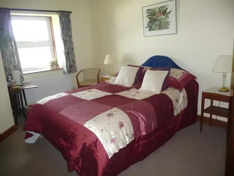 Double bed with blue headboard and burgundy patchwork bedding