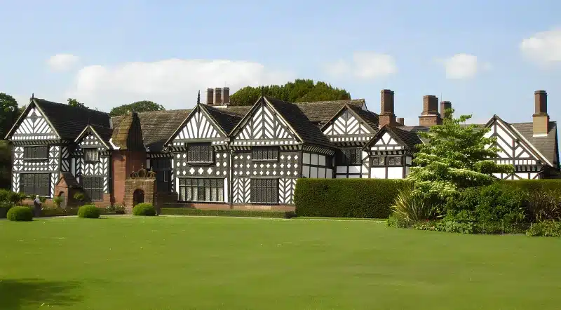 Speke Hall in Speke, Liverpool: a long black-and-white timber-framed house with patterned gables, tall brick chimneys and a wide lawn.