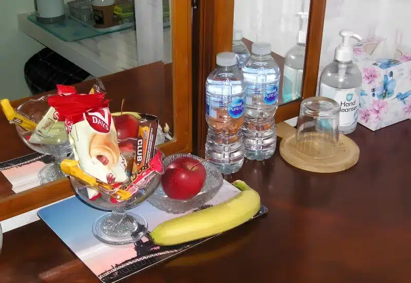 Water, fruit and snacks on the desk in the room at Liverpool Airport Rooms.