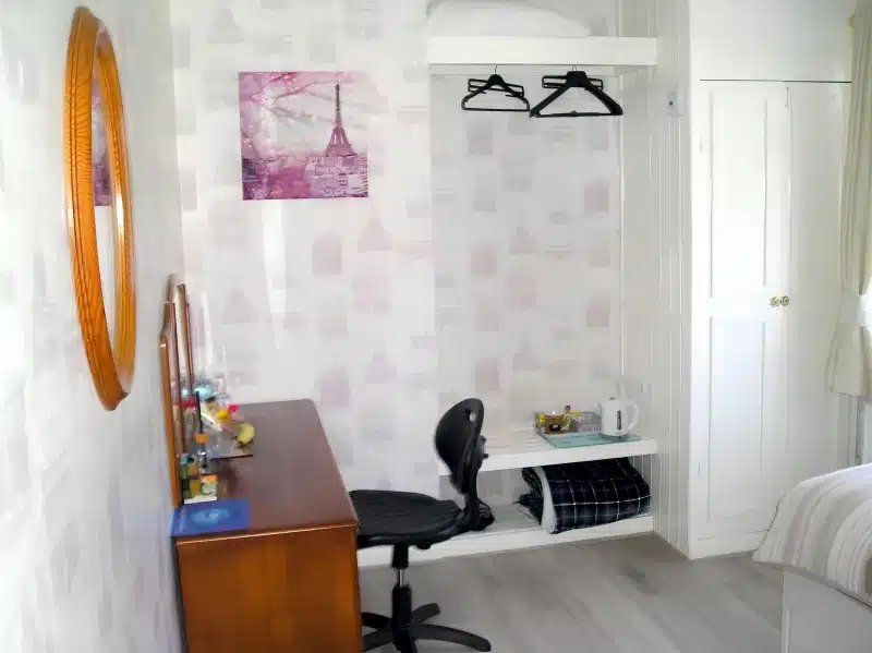 A wooden desk, office chair and hanging rail in the room at Liverpool Airport Rooms.