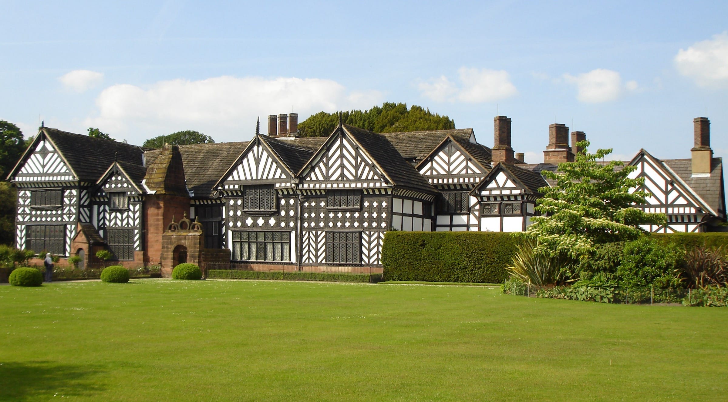 Speke Hall in Speke, Liverpool: a long black-and-white timber-framed house with patterned gables, tall brick chimneys and a wide lawn.