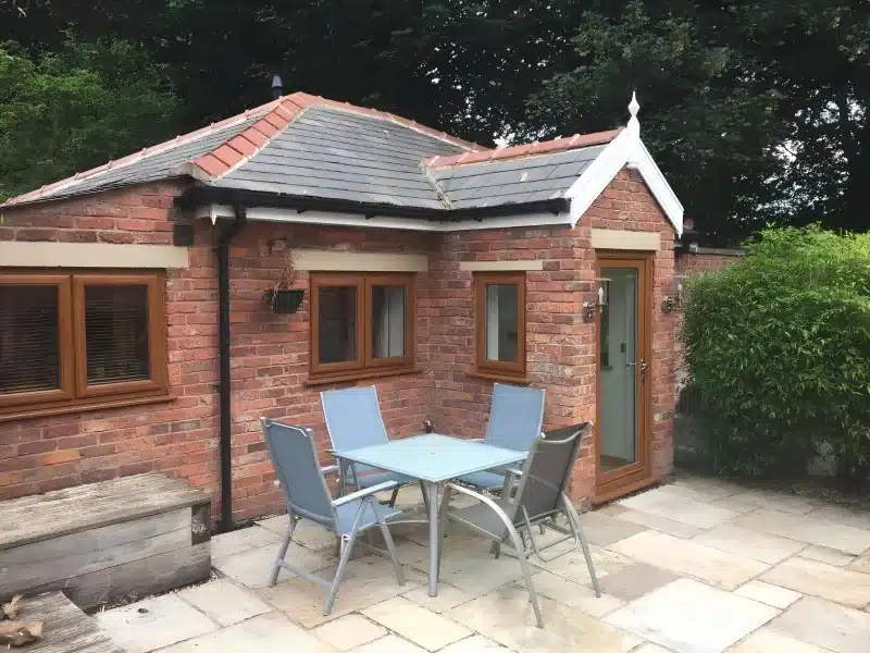 The lodge's brick front, wooden door and patio table under a slate roof.
