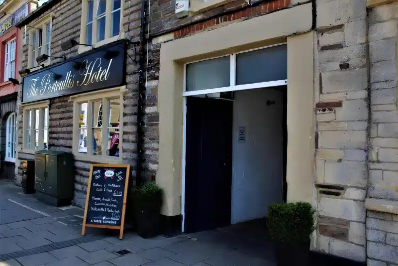 The stone front of The Portcullis Hotel on Horse Street, with a black sign and a dark doorway.