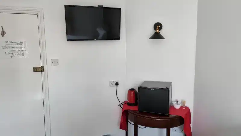 A television, kettle and mini-fridge, with a door notice for The Portcullis Hotel.