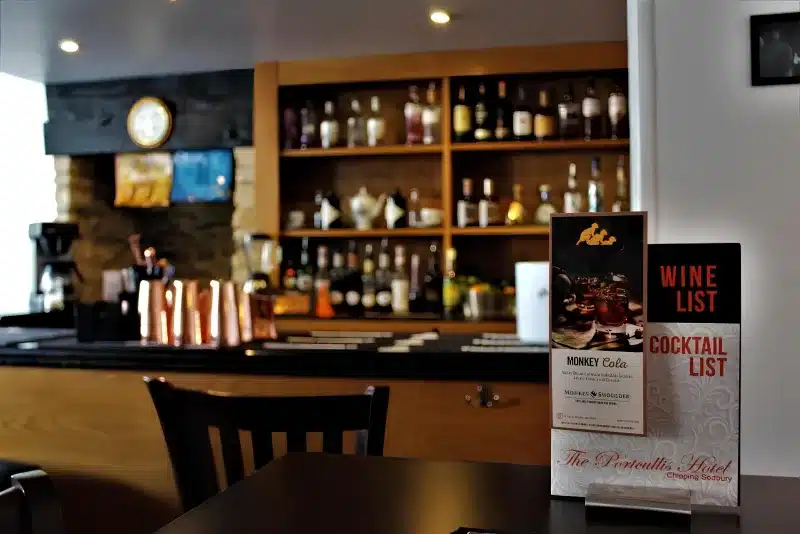 The bar, with wine and cocktail lists and a stand reading The Portcullis Hotel, Chipping Sodbury.