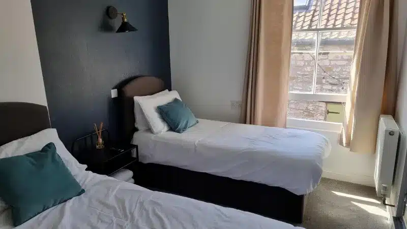 Two single beds with teal cushions.