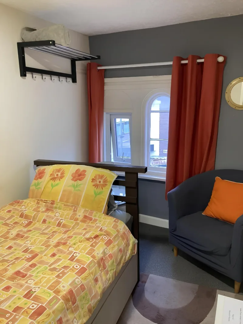 Single bedroom with colourful bedding and a chair