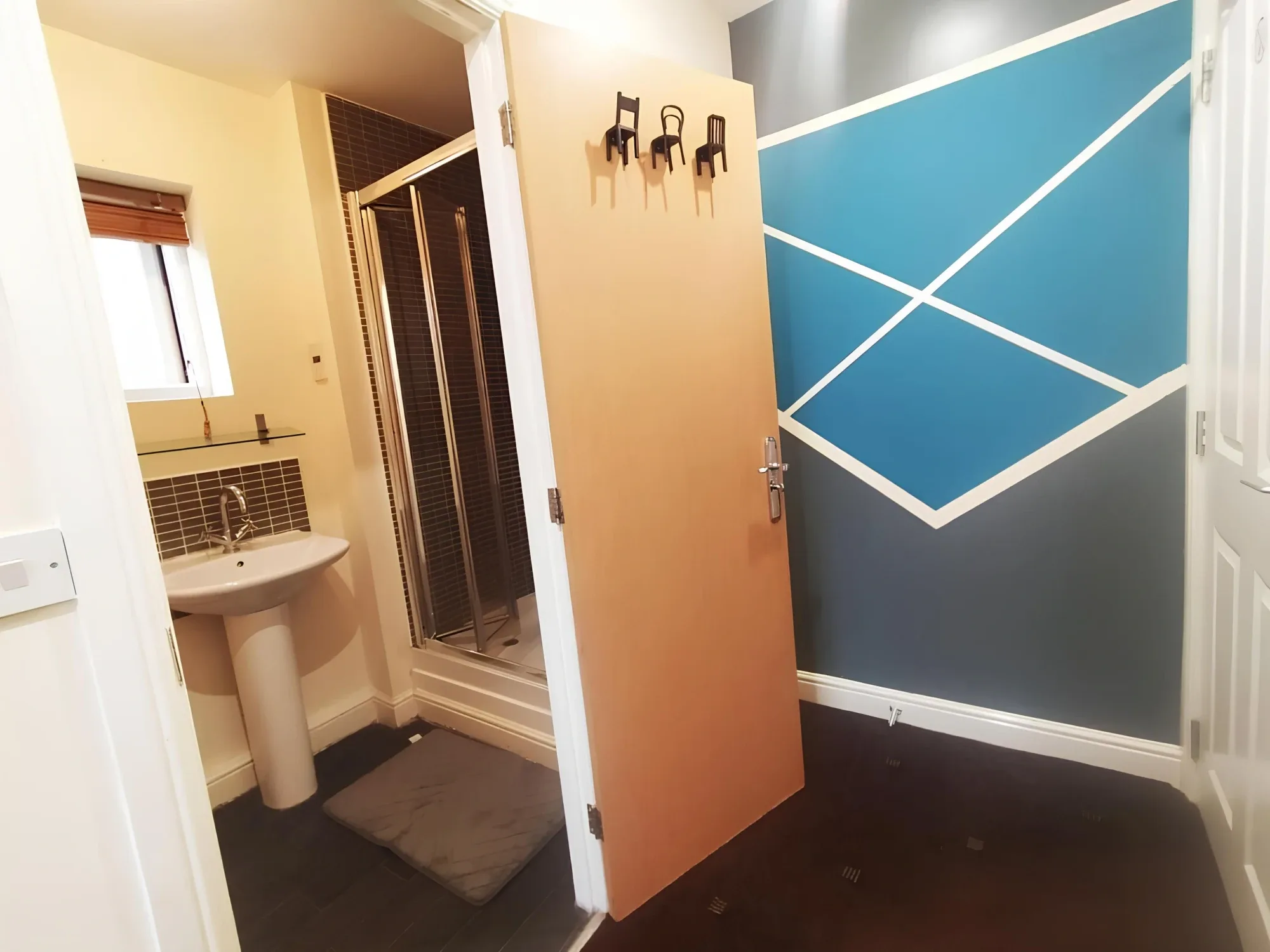 Bathroom doorway and shower beside a geometric wall in a private-bathroom double room