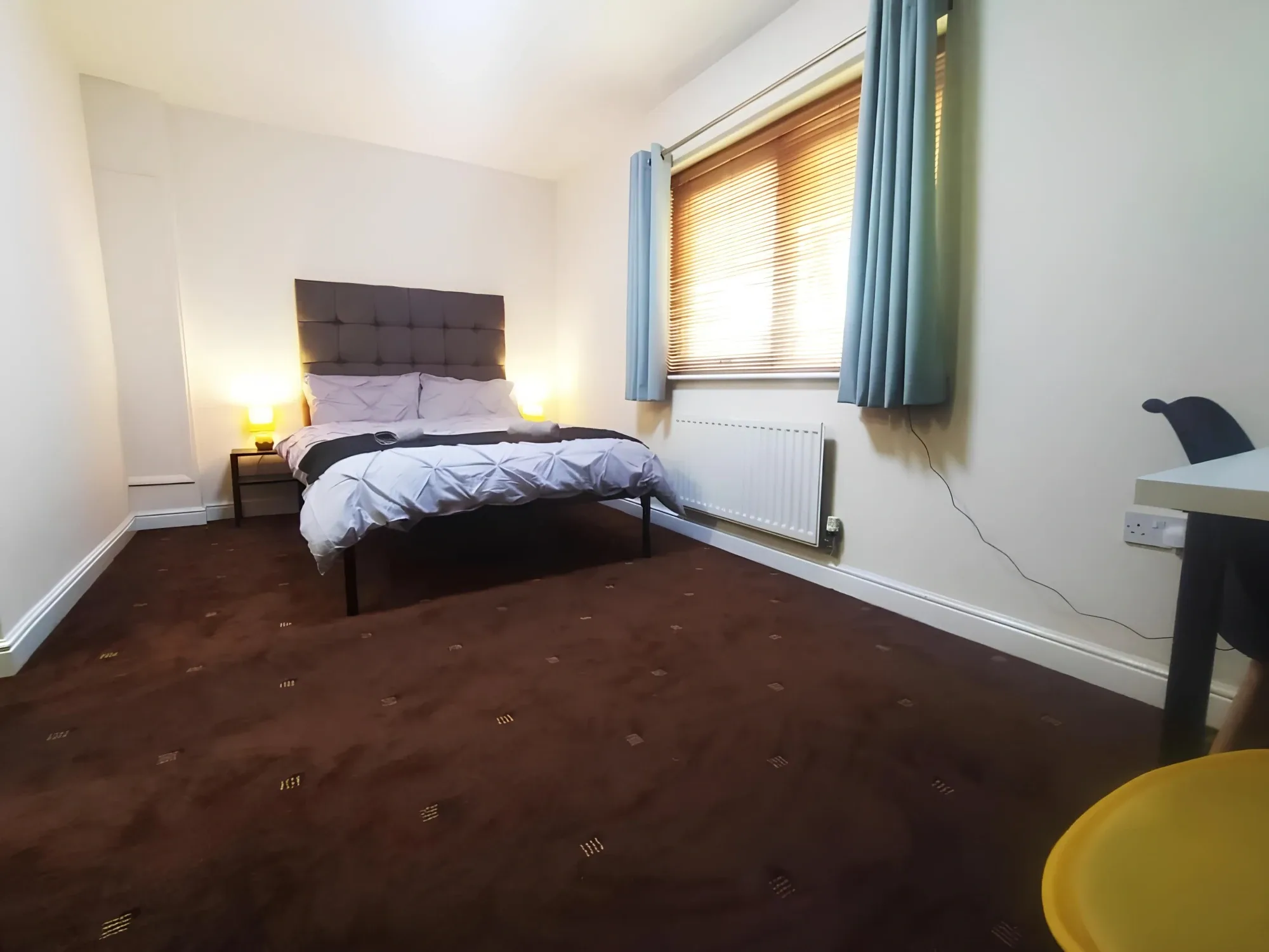 Wider view of a private-bathroom double room with a window and desk