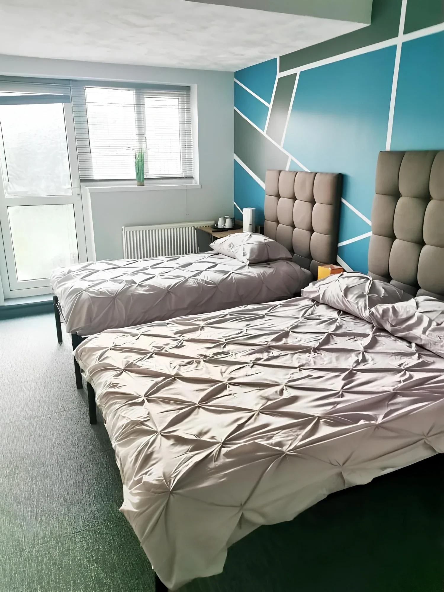 Beds beside a teal geometric wall in the Double or Twin Room with Private Bathroom