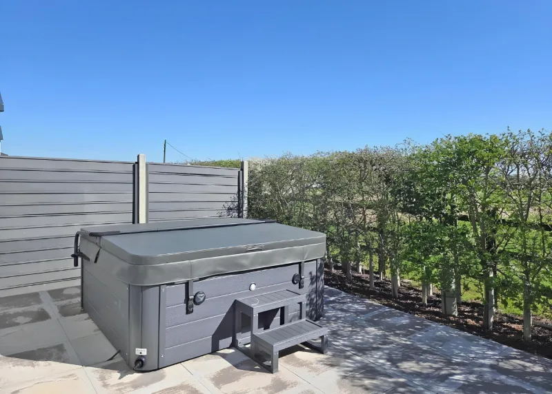 Covered hot tub beside a wooden screen