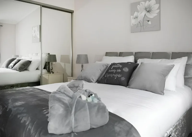 Double bedroom with grey bedding and a mirror