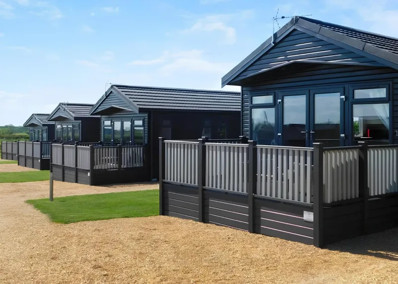 Dark timber lodges and gravel path beside the lawn