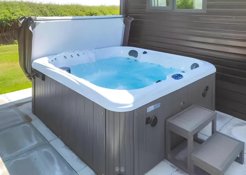 Outdoor hot tub with steps beside a dark timber lodge