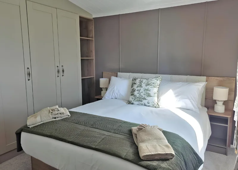 Double bed with green bedding in a timber-toned bedroom