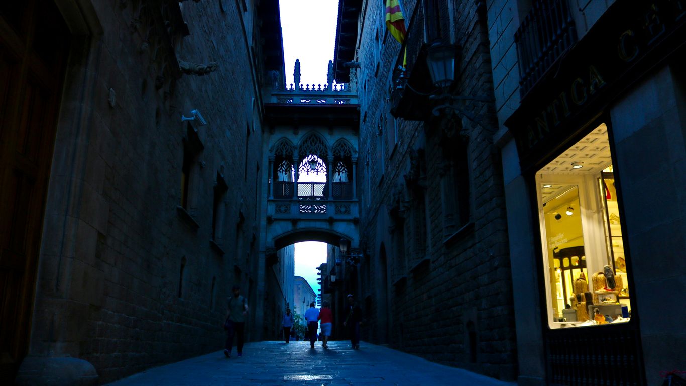 A narrow street with stone buildings and an overhead stone bridge